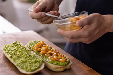 Chef cook hands making fresh diet avocado toast with seafood shrimps. Healthy vitamin breakfast.