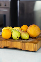 Fresh fruits on wooden cutting board. Fruit healthy salad preparation. Mango, orange, apple and pear.