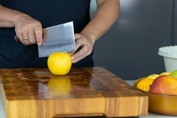 Chef cook cutting fresh apples for fruit salad on wooden cut board