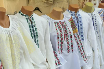 Deurstickers Moldovan embroideries. Men's and women's Moldovan embroidered shirts at the fair. Balkan embroidered national traditional costume clothes © natalyamatveeva