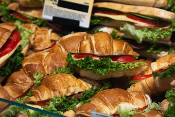 Sandwich croissant with cheese, tomatoes and lettuce on a supermarket showcase