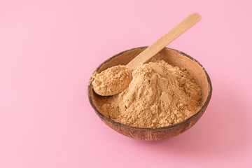 Closeup image of raw maca root powder on pastel pink background