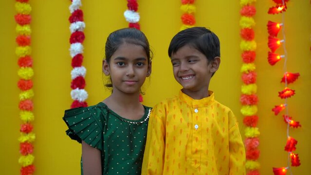 Portrait of happy indian young kids or bothers and sister wearing traditional cloths having fun or celebrating festival like diwali or rakshabandhan