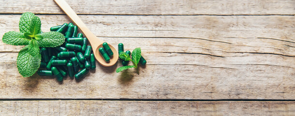 Green capsules, herbal medications, sedatives with mint. Selective focus.