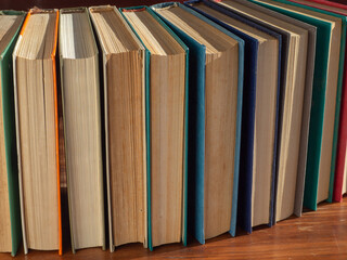 Old books in colorful hardcovers close-up on a wooden shelf