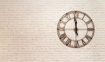 Metal thin clock on brick wall background with copy space. New Year's Eve.