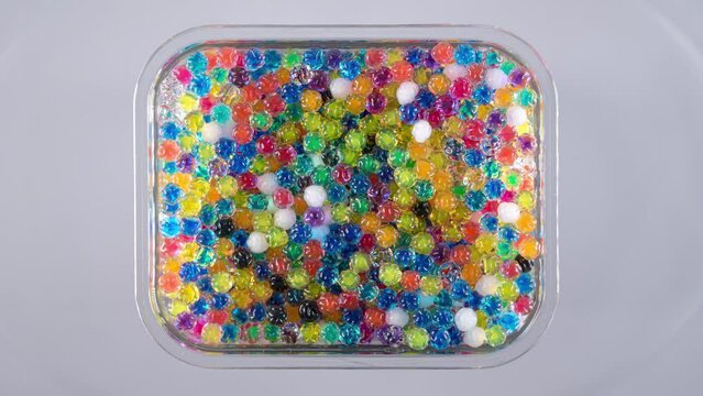 4K Time Lapse of Water beads growing in water close-up, top view. Texture of Hydrogel jelly balls - many colorful orbeez.