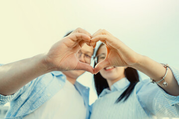 Closeup of couple making heart shape with hands-beautiful sweet Chinese  family smiling.young girl and boy lovers outdoor-Focus on hand.Love Concept , youth guys outdoors