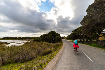 Obraz premium hiker girl with backpack cycling around rottnest island in western australia, near perth, riding a bicycle in australia