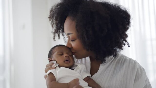 Close up portrait of beautiful young African American mother holding kissing sleep newborn baby in hospital. Healthcare medical love black afro woman lifestyle mother's day, breast concept 