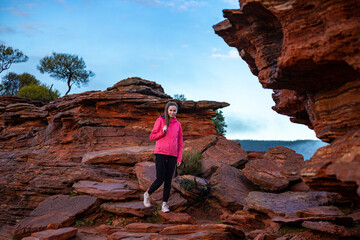 long-haired girl walks along a ridge on the red rocks of kalbarri national park in western australia; hiking in the wilderness, australian outback