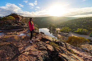 Fototapeta premium long-haired girl walks along a ridge on the red rocks of kalbarri national park in western australia; hiking in the wilderness, australian outback