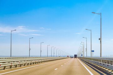 Automobile bridge across the Kerch Strait or Crimean bridge. Asphalt road with marking and road lampposts with alarm annunciators. 151 km rosautodor on road sign (translation from Russian).