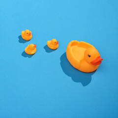 Creative layout with rubber duck mother and ducklings. Bright blue background with shadow. Visual summer trend. Minimalistic aesthetic still life. Fresh idea
