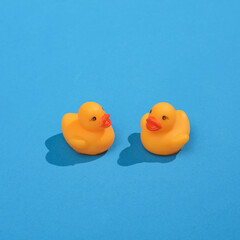 Creative layout with rubber ducklings. Bright blue background with shadow. Visual summer trend. Minimalistic aesthetic still life. Fresh idea