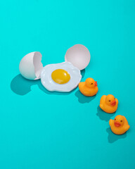 Creative layout with hatched ducklings from eggs and scrambled eggs. Bright blue background with shadow. Visual trend. Minimalistic aesthetic still life. Fresh idea