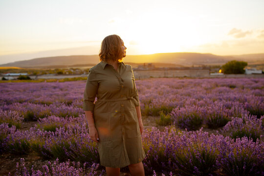 Beautiful plus size woman dressed dress and straw hat walking in the lavender flowers field, enjoy the aromatherapy