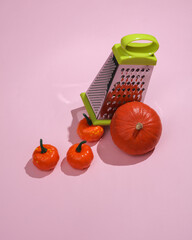 Grater with pumpkin on pink pastel background with shadow. Minimal halloween concept