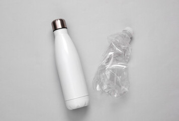 Thermos steel bottle and crumpled plastic bottle on a gray background. Eco concept
