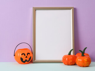 Photo frame with a white sheet of paper (mockup) and halloween decor on a pastel background. Minimal still life