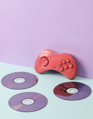Creative layout with cd discs and retro gamepad on pastel background. Conceptual pop. Minimal still life