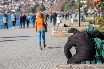 An older man trying to stand up from the bench
