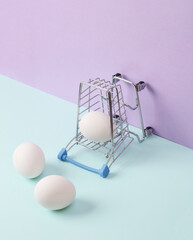 Creative layout with mini shopping trolley and eggs on pastel background. Conceptual pop. Minimal still life.