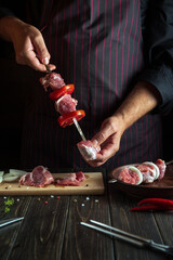 Cooking shish kebab from raw lamb meat in the kitchen with the hands of a cook. Asian traditional cuisine.