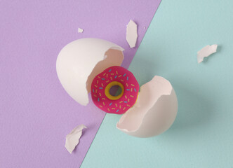 Donut hatched from egg on pastel background. Creative layout