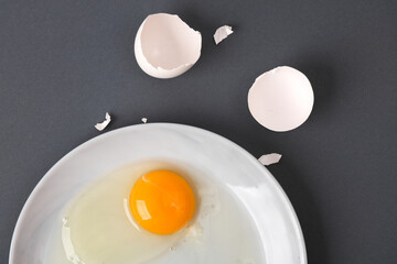 Creative layout. Raw egg with eggshell on gray background. Conceptual pop. Minimal food still life.