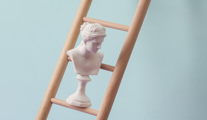 Venus bust on Wooden ladder, pastel background. Leadership, career growth, business concept....