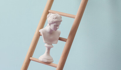 Venus bust on Wooden ladder, pastel background. Leadership, career growth, business concept. Creative minimal layout © splitov27