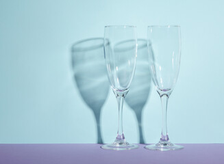 Creative layout with empty champagne glass on two tone pastel background. Visual trend. Minimalistic aesthetic still life. Reflection, shadows
