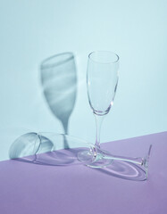 Creative layout with empty champagne glass on two tone pastel background. Visual trend. Minimalistic aesthetic still life. Reflection, shadows
