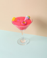 Creative layout, cocktail glass with neon slime, toy ice cream and donut on two tone pastel background. Visual trend. Minimalistic aesthetic still life. Party concept.