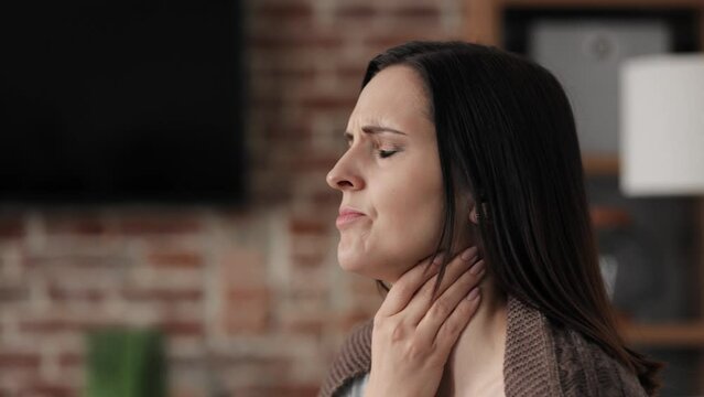Portrait of ill young woman at home having cough and sore throat. First symptoms of cold and flu virus, pneumonia, bronchitis and respiratory tract infection. Seasonal virus disease.