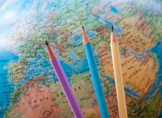 Colorful pencils on a world map background.