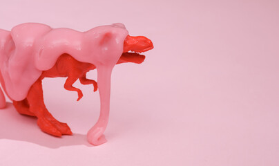 Creative layout, toy tyrannosaurus with slime on pink background with shadow. Visual trend. Fresh idea. Concept pop