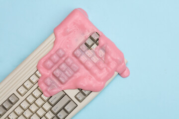 Creative retro layout, Old keyboard with slime on blue pastel background. Visual trend. Fresh idea