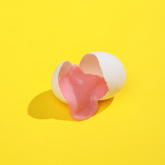 Creative layout with slime in broken chicken egg shell. Bright yellow background with shadow. Visual trend. Easter, food conceppt. Minimalistic aesthetic still life. Fresh idea