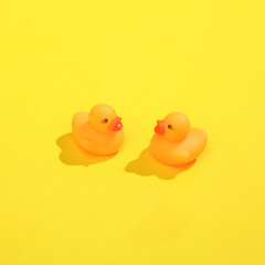 Creative layout with rubber ducklings. Bright yellow background with shadow. Visual summer trend. Minimalistic aesthetic still life. Fresh idea