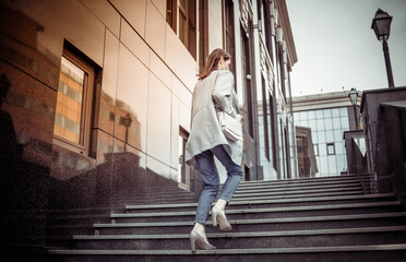 Modern business woman climbs the stairs up near the business building. Lifestyle