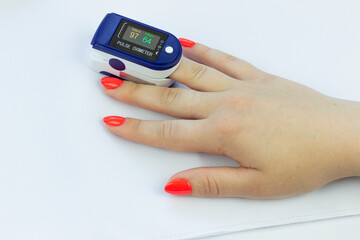 pulse oximeter on a woman's finger close-up, on a white background