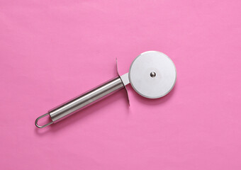 Steel round knife for cutting pizza on pink background