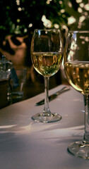 Reflection of the sun's rays and the surrounding space in a glass of white wine standing on a restaurant table