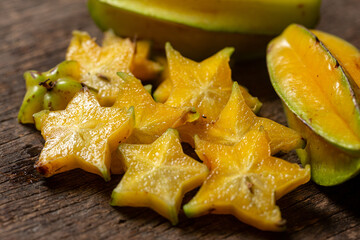 Organic carambola Asian fruit whole in a wicker basket and cut into a pine, carambola, grown on an organic farm on a rustic wooden table top, top view with space for writing
