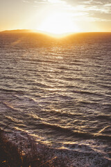 Beautiful sunset of wavy water on the seashore in Greece with mountains in the distance.