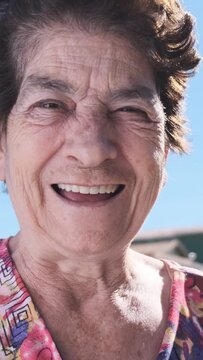 Smiling old woman. Beautiful senior woman looking at the camera with a warm friendly smile and attentive expression. Elderly woman laughing. Vertical video.