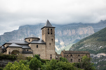 Fototapeta na wymiar Church of San Salvador in Torla - Ordesa, with Monte Perdido in the background on a foggy day. Pyrenees