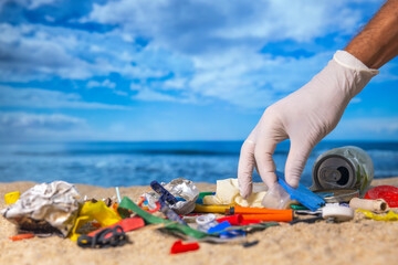 A beach full of trash with gloved hand